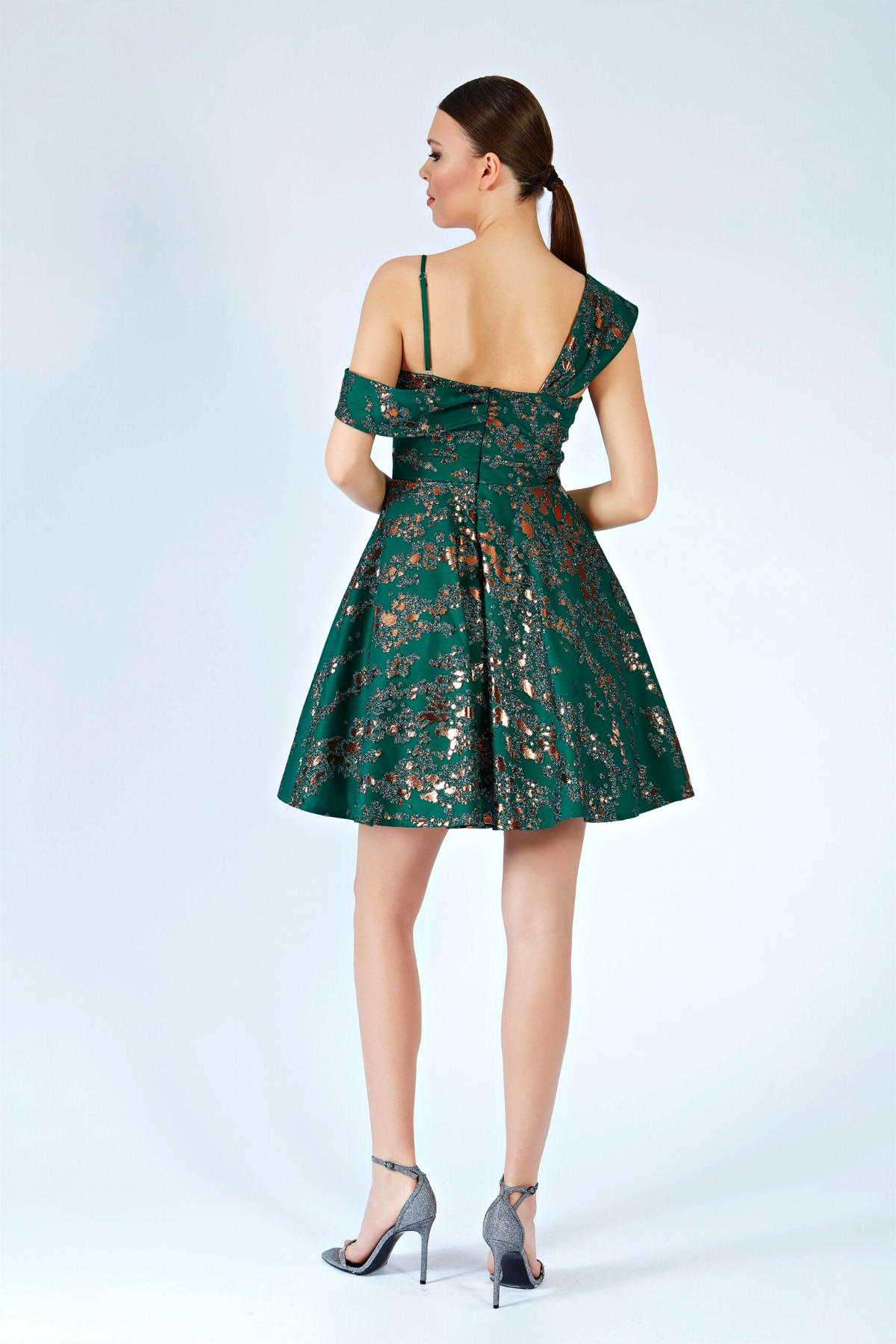 Abito corto svasato verde smeraldo con fantasia glitterata e spalla cadente, di moda-mania, perfetto per eventi estivi.