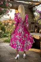 Abito midi fucsia svasato con fantasia floreale, maniche a sbuffo e cintura allacciabile in vita, firmato Moda-Mania.