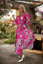 Abito midi fucsia svasato con fantasia floreale, maniche a sbuffo e allacciatura in vita, prodotto da Moda-Mania