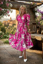 Abito midi fucsia svasato con fantasia floreale, maniche a sbuffo e cintura allacciabile in vita, marca Moda-Mania.