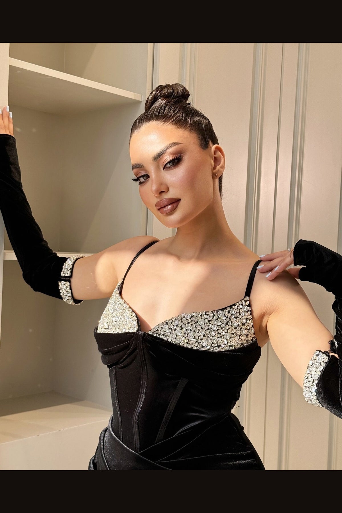 Abito lungo nero in velluto aderente di Moda-Mania con cristalli, guanti eleganti e spacco laterale, dettaglio sofisticato.