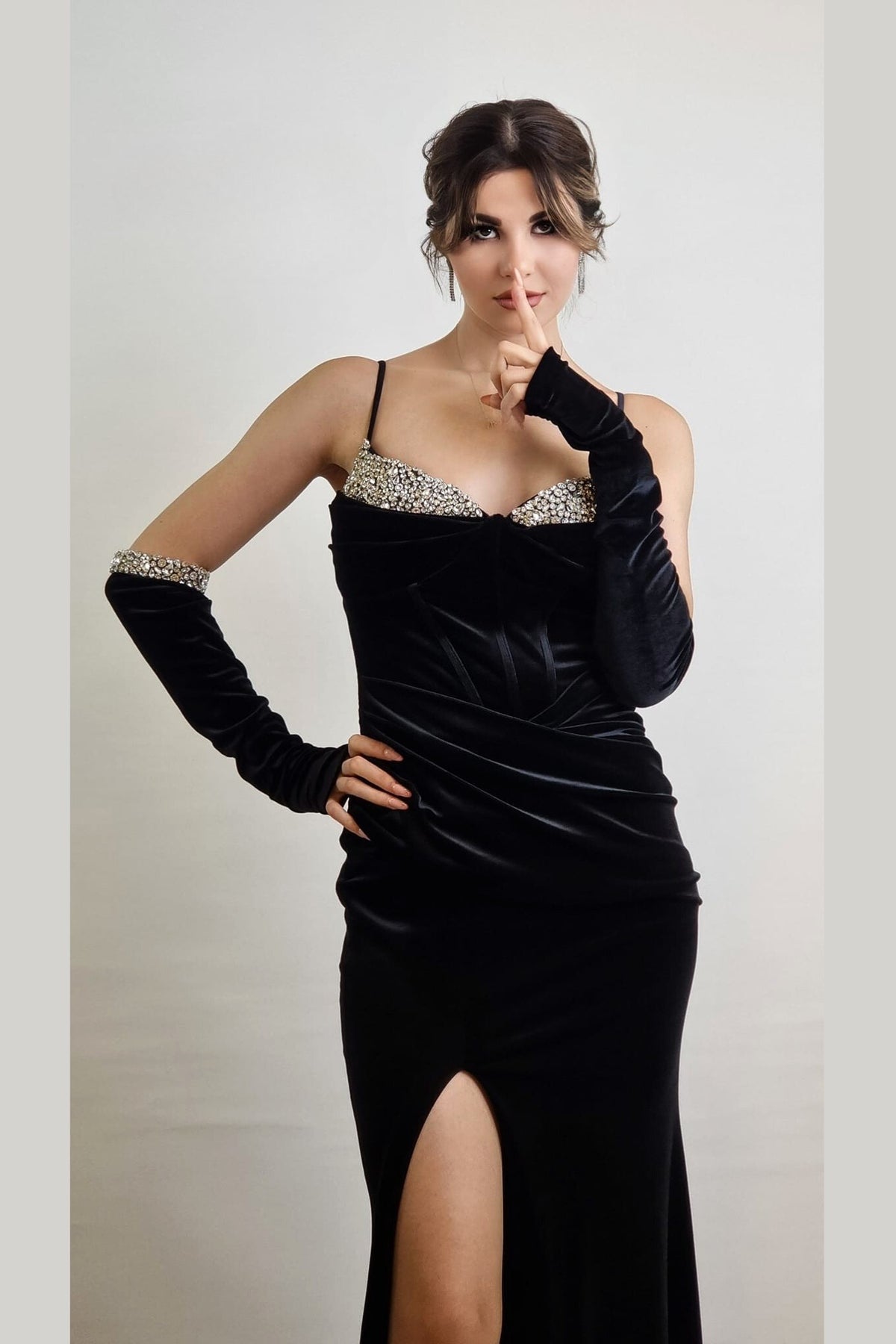 Abito lungo aderente nero in velluto con cristalli, spacco laterale e guanti eleganti, firmato Moda-Mania.