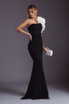 Abito lungo aderente nero monospalla di Moda-Mania con fiore bianco 3D e spacco laterale, elegante e femminile.