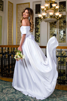Abito lungo svasato bianco Pretty Girl con spacco laterale e dettaglio fibbia gioiello, vestito elegante e femminile.