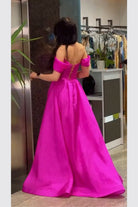Abito lungo svasato da cerimonia fucsia con scollo a barchetta e stringhe regolabili, Moda-Mania, dettagli eleganti e femminili.