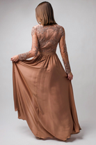 Abito lungo svasato dorato bronzo Moda-Mania con tessuto lucido, spacco laterale e corpetto in tulle ricamato.