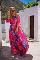 Abito lungo svasato estivo fucsia con fantasia floreale blu, scollo a barchetta, in tessuto satinato, di Moda-Mania.
