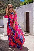 Abito lungo svasato estivo fucsia con fantasia floreale blu, scollo a barchetta, tessuto satinato, marca Moda-Mania.