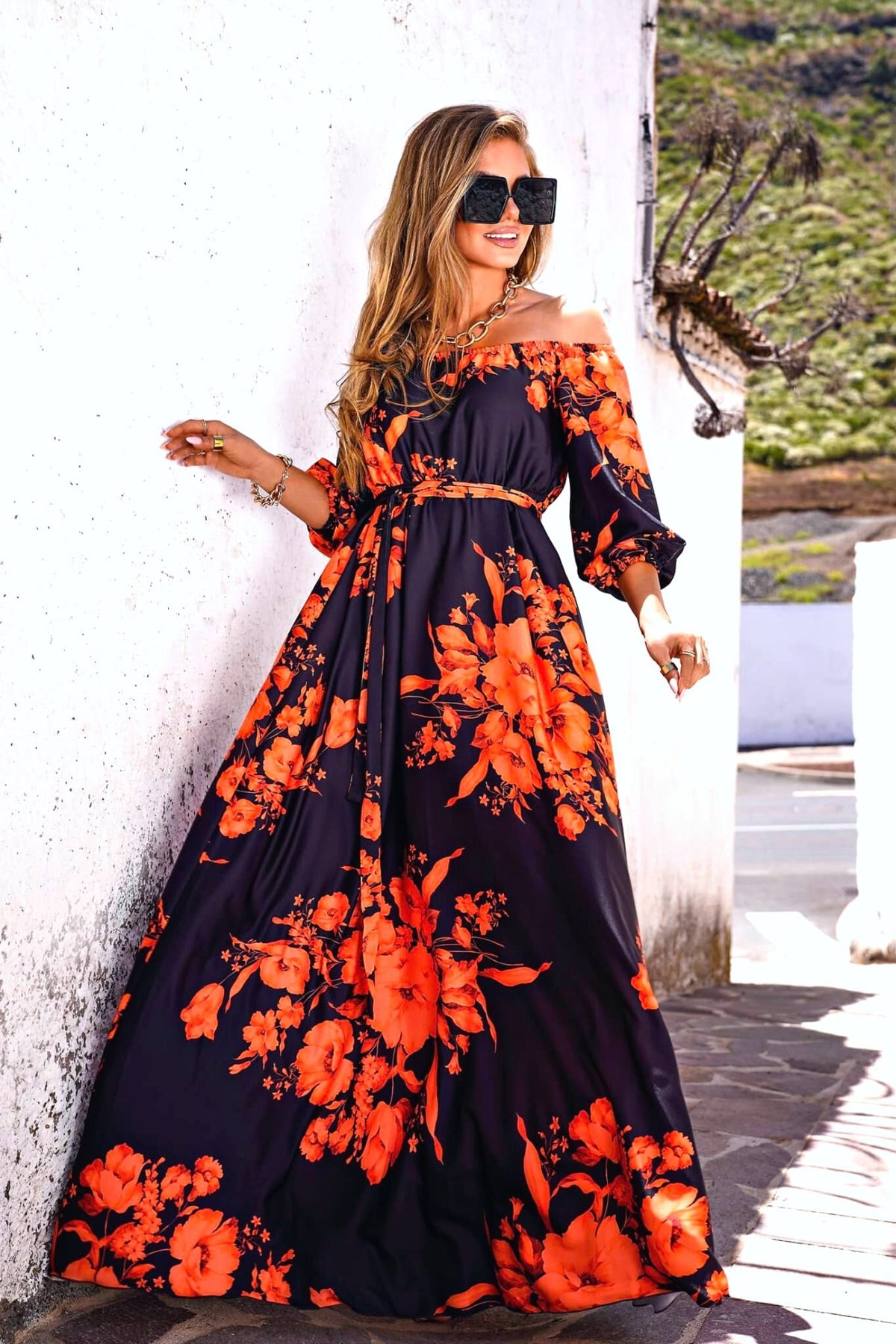 Abito lungo svasato estivo nero e bianco con fantasia floreale arancione e fucsia, scollo a barchetta in tessuto satinato.