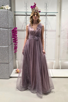 Abito lungo svasato lilla in tulle glitterato con spacco e decorazioni floreali, ideale per occasioni eleganti.