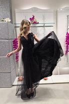 Abito lungo svasato nero in tulle glitterato con spacco e dettagli floreali, firmato Moda-Mania, visibile con decorazioni eleganti.