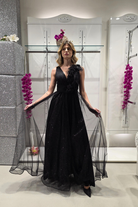 Abito lungo svasato nero in tulle glitterato con spacco e fiori decorativi, firmato Moda-Mania, visibile in dettaglio.