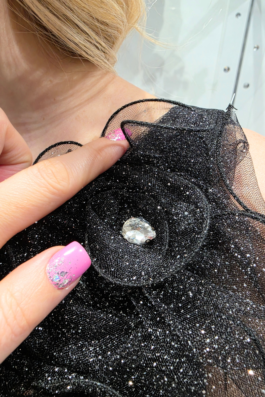 Abito lungo nero svasato in tulle glitterato con spacco e decorazioni floreali, design elegante e femminile.