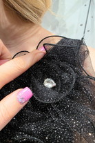 Abito lungo nero svasato in tulle glitterato con spacco e decorazioni floreali, design elegante e femminile.