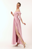 Abito lungo svasato rosa in taffetà di Moda-Mania con scollo a barchetta, spacco laterale e fiocchi decorativi.