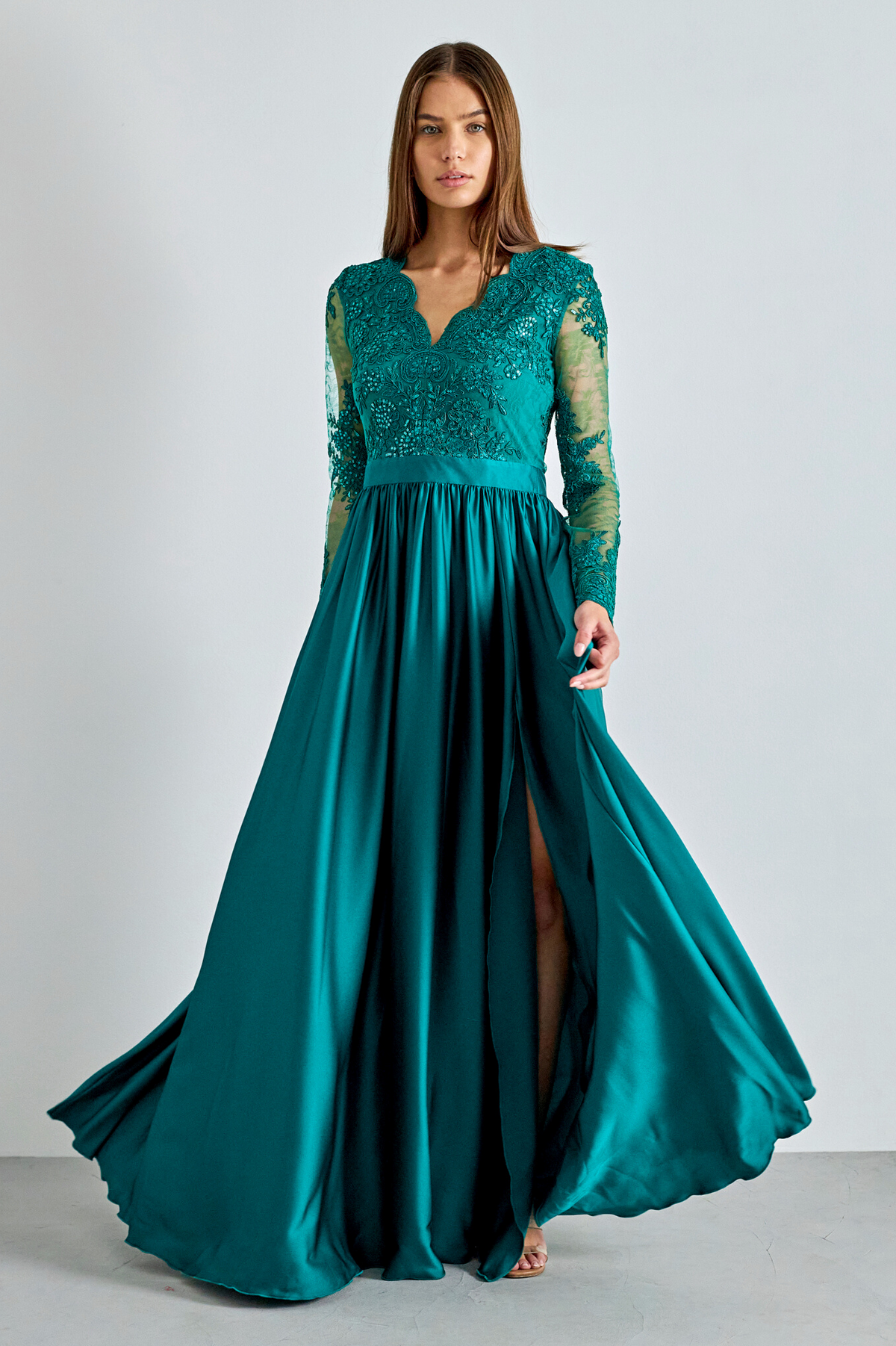 Abito lungo svasato verde in tessuto lucido con spacco laterale e corpetto in tulle ricamato, da Moda-Mania.