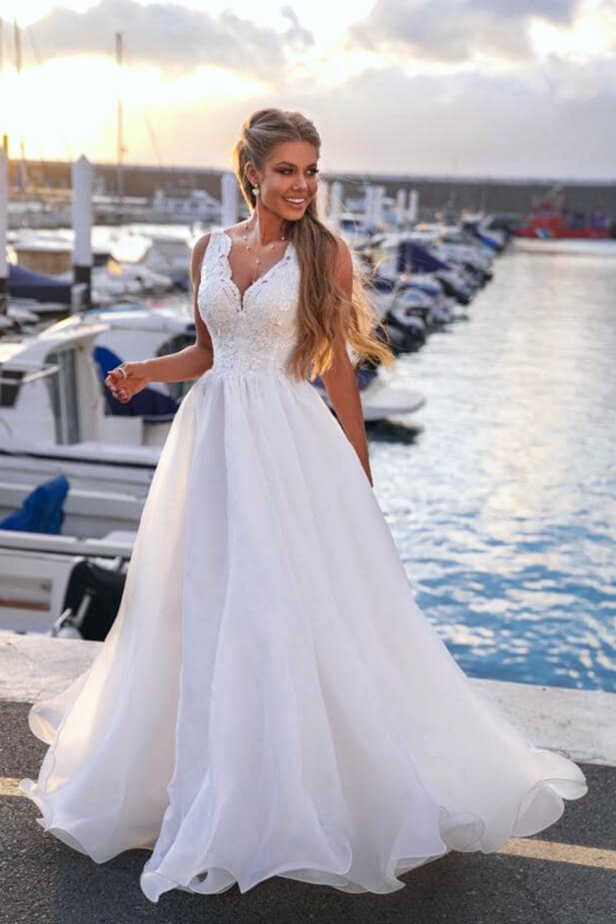 Abito lungo bianco da cerimonia Moda-Mania con corpetto ricamato e gonna ampia in organza, sfondo rosa cipria.