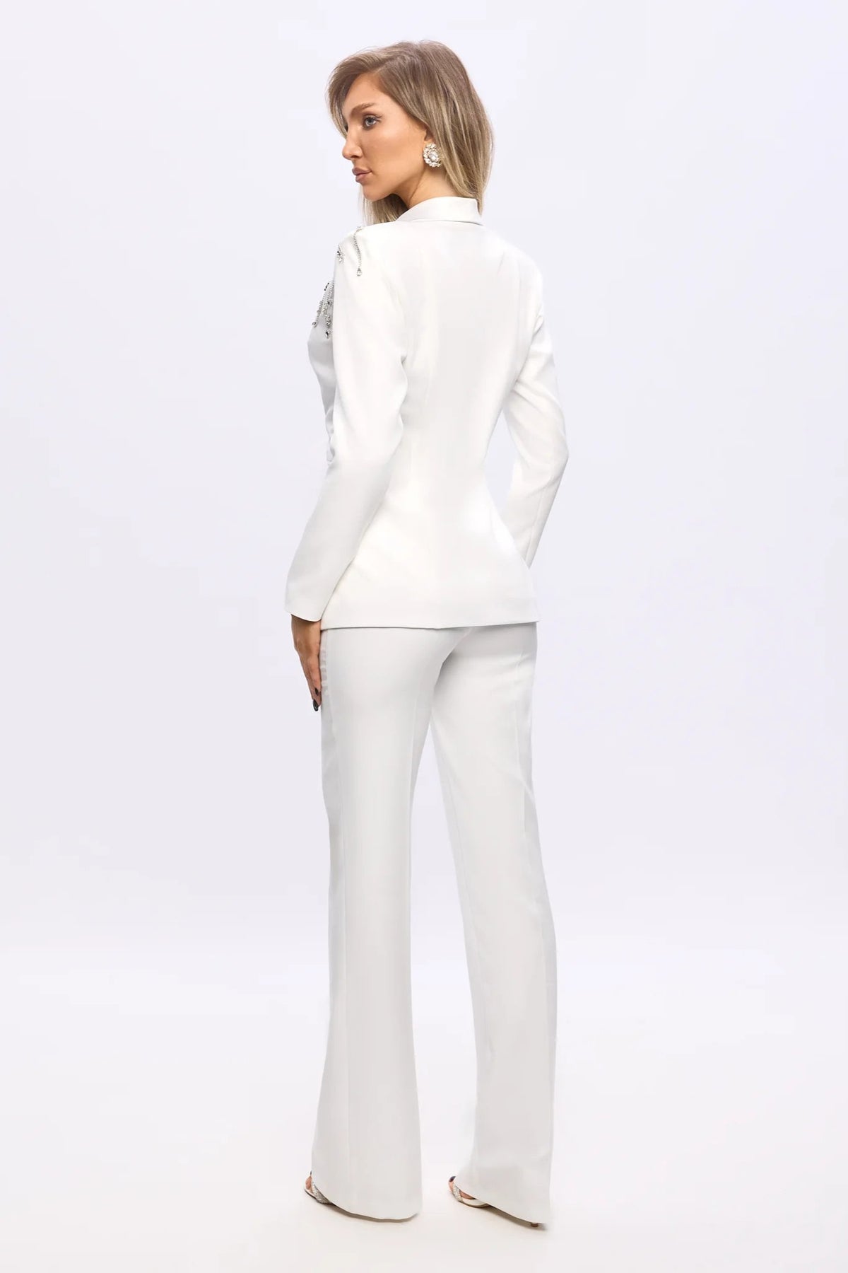 Completo tailleur Bby bianco con giacca a V con piume e applicazioni argento, pantaloni a gamba larga, eleganti e sofisticati.