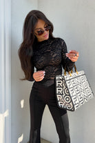 Blusa aderente nera a maniche lunghe in pizzo elasticizzato con fantasia floreale, firmata Moda-Mania.