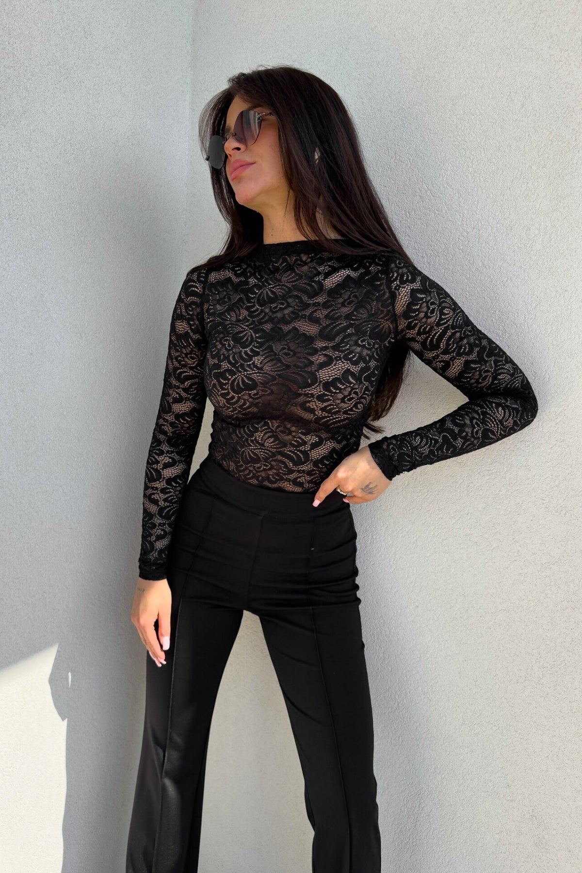 Blusa aderente nera Moda-Mania con maniche lunghe in pizzo elasticizzato fantasia floreale, dettaglio elegante e femminile.