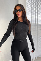 Blusa aderente nera a maniche lunghe in tessuto glitterato elasticizzato, moda-mania, dettaglio tessuto e vestibilità.