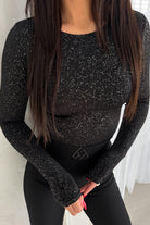 Blusa aderente nera a maniche lunghe in tessuto glitterato stretch elasticizzato, moda-mania, dettaglio del tessuto brillante.