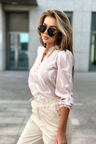 Blusa beige Moda-Mania a stampa astratta bianca con scollo a V e bottoncini, tessuto leggero e design elegante.