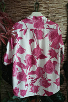 Blusa bianca Moda-Mania con fantasia floreale fucsia, maniche tre quarti e bottoni dorati, dettagli eleganti e femminili