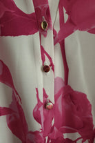 Blusa bianca floreale fucsia Moda-Mania con maniche tre quarti e bottoni dorati, tessuto leggero e stile femminile.