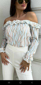 Blusa celeste a fantasia astratta con scollo a barchetta e rifiniture rouches, brand Moda-Mania, vestibilità elegante e femminile.