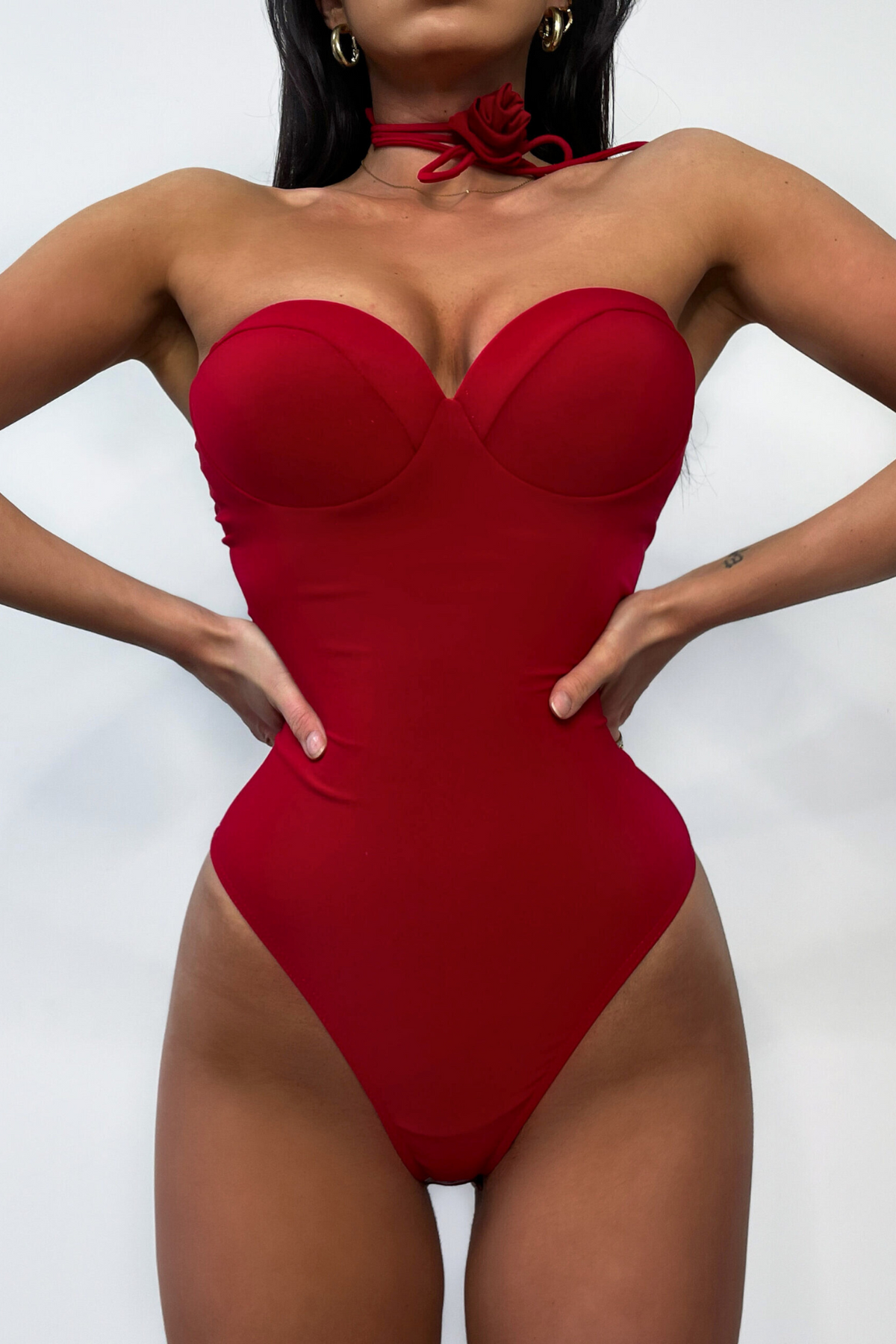 Body elasticizzato rosso Moda-Mania con coppe, collarino in tessuto e fiore decorativo, indossato in dettaglio.