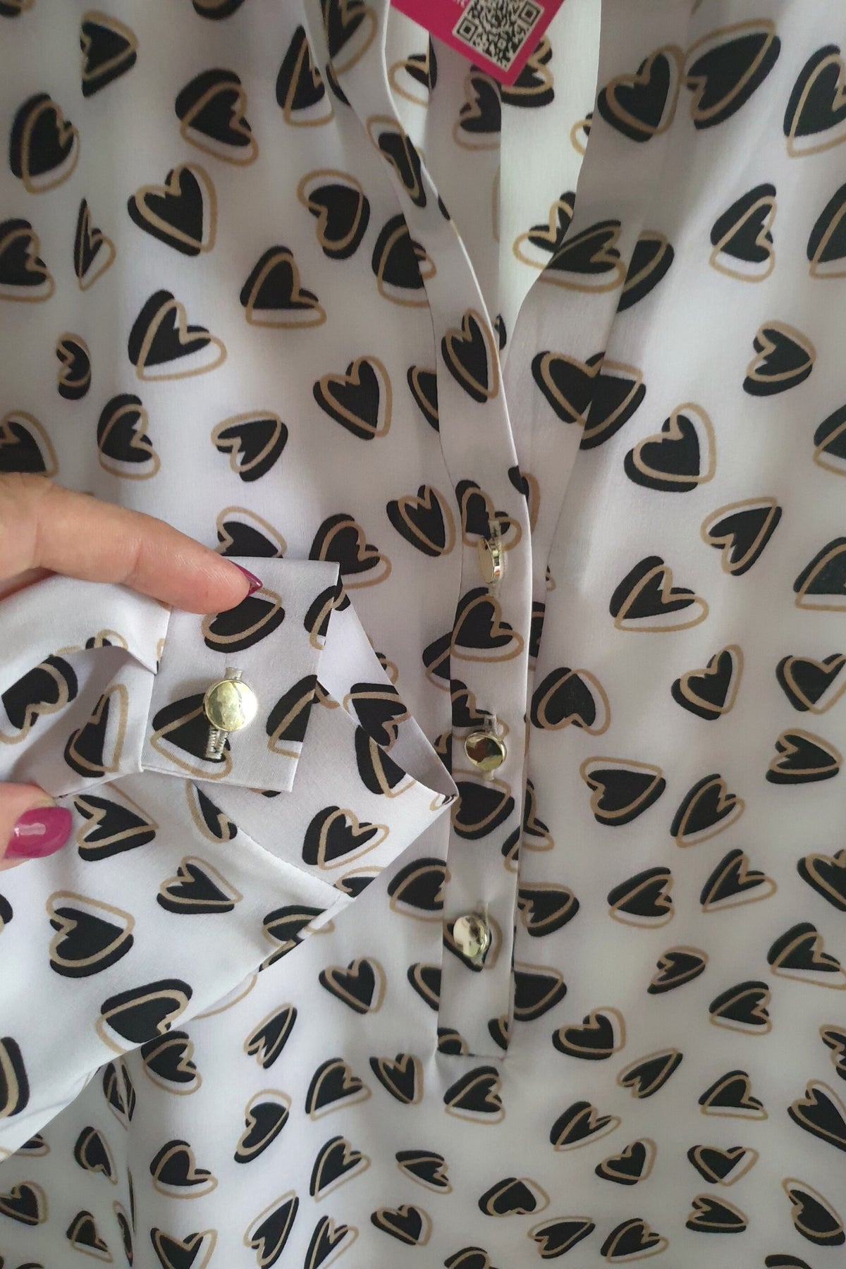 Camicia bianca a fantasia cuori neri e beige di Moda-Mania, scollo a V con bottoni dorati, tessuto leggero e stile elegante.
