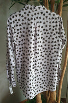 Camicia bianca Moda-Mania con fantasia a cuori neri e beige, scollo a V e bottoni dorati, tessuto leggero e stile elegante