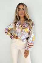 Camicia casual elegante Moda-Mania con fantasia floreale, scollo a V e dettagli di volants decorativi, tessuto leggero e femminile.