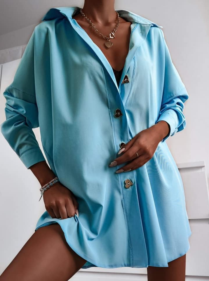 Camicia oversize celeste Moda-Mania con bottoni dorati a forma di cuore, lunga e ampia, tessuto leggero e morbido.