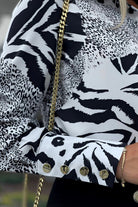 Camicia elegante Moda-Mania a fantasia animalier bianco e nero con bottoni dorati, maniche lunghe e design raffinato.