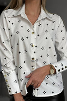 Camicia elegante bianca a fantasia nera con bottoni dorati, stile fashion, marca Moda-Mania, vista frontale.