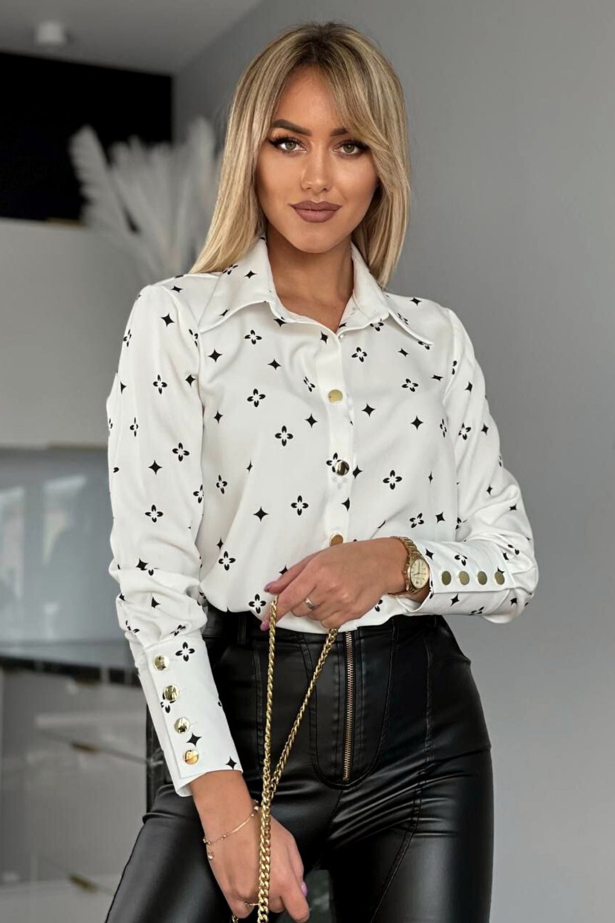 Camicia elegante bianca con fantasia nera, bottoni dorati, marca Moda-Mania, mostra dettagli della camicia con bottoni dorati.