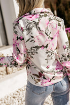 Camicia elegante bianca Moda-Mania con fantasia floreale rosa e fucsia e bottoni dorati, dettagli raffinati e stile sofisticato.