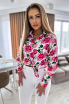Camicia elegante bianca Moda-Mania con fantasia floreale rosa, bottoni dorati e dettagli raffinati, ideale per un look sofisticato.