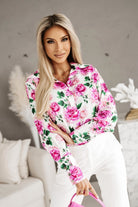 Camicia elegante bianca Moda-Mania con fantasia floreale rosa, dettagli di bottoni dorati e tessuto leggero.