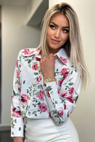 Camicia elegante bianca Moda-Mania con fantasia floreale rossa e rosa, bottoni dorati, tessuto leggero e dettagli raffinati.