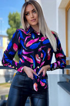 Camicia elegante nera Moda-Mania con fantasia foglie blu e fucsia, bottoni dorati, tessuto leggero e stile raffinato.