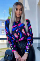 Camicia elegante nera Moda-Mania con fantasia foglie blu e fucsia e bottoni dorati, dettagli sofisticati e tessuto leggero.