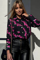 Camicia elegante nera Moda-Mania con fantasia di piccole rose fucsia e bottoni dorati, tessuto leggero e dettagli raffinati.