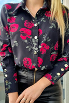 Camicia elegante nera Moda-Mania con fantasia di rose rosse, foglie verdi e bottoni dorati, tessuto morbido e dettagli raffinati.