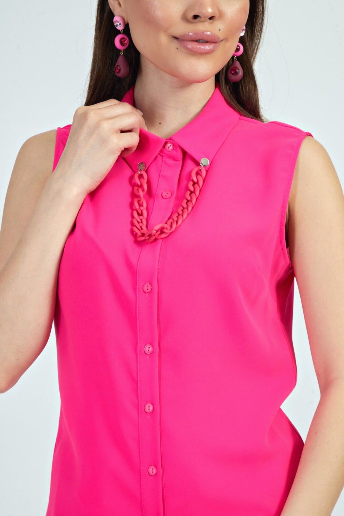 Camicia fucsia senza maniche di Moda-Mania con catenella nera rimovibile, dettaglio accessoriato e stile elegante.