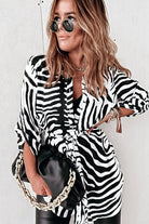 Camicia lunga bianca a fantasia zebrata nera con spacchi laterali e cinturino, firma Moda-Mania, dettagli visibili in foto.