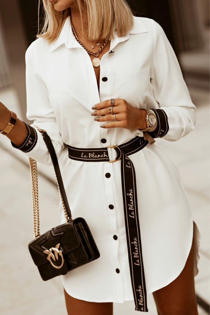 Camicia lunga bianca asimmetrica accessoriata con cintura e polsini neri