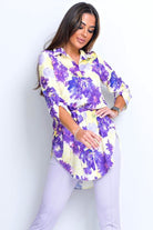 Camicia lunga Moda-Mania gialla pastello con fantasia floreale violetto, spacchi laterali e cinturino, tessuto leggero e elegante.